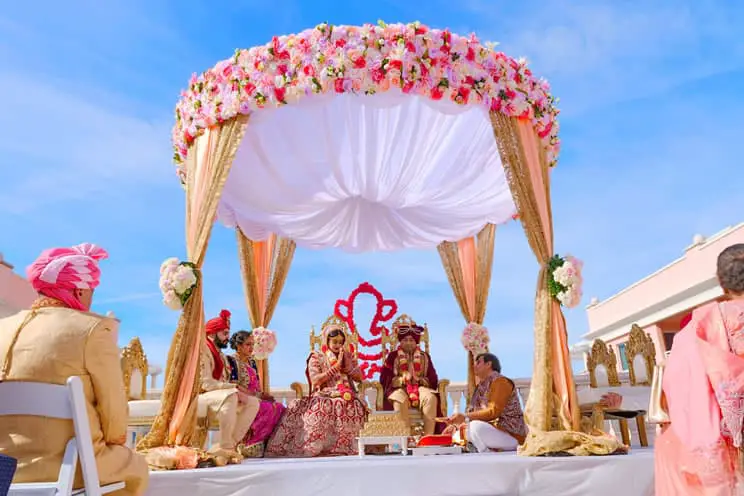 Hindu couple sat outdoors in front of Ganesh being married