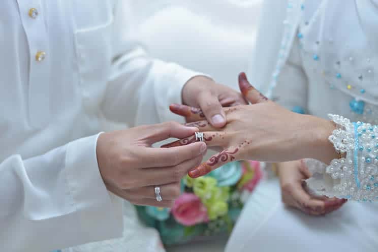 Muslim groom putting ring on muslim brides ring finger.