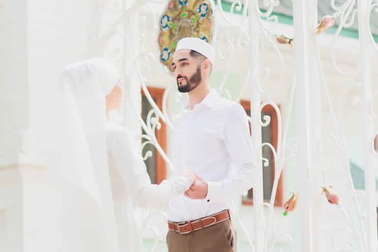 Muslim groom holding hands with bride and staring into each others eyes