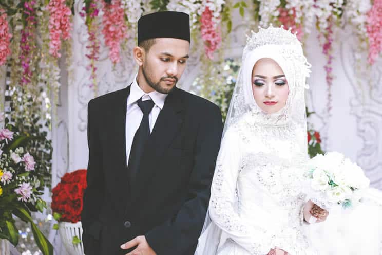 Muslim bride and groom standing back to back