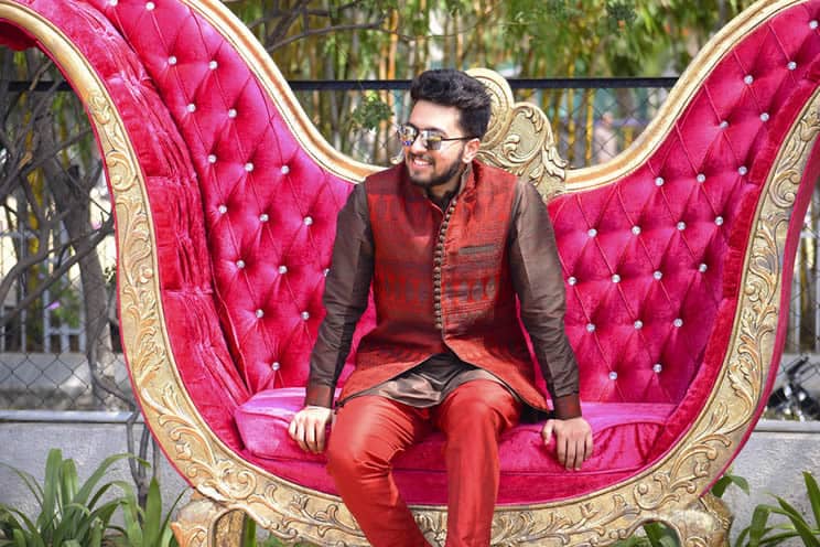 Indian man wearing sherwani seated in extravagant chair